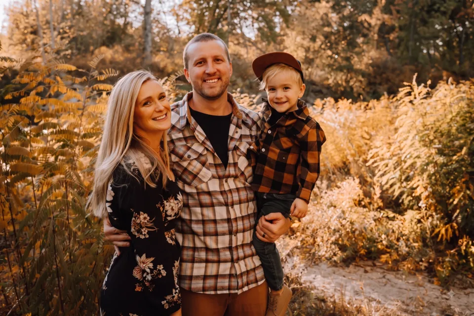 Jessy Gilger with his wife and son outdoors among autumn trees