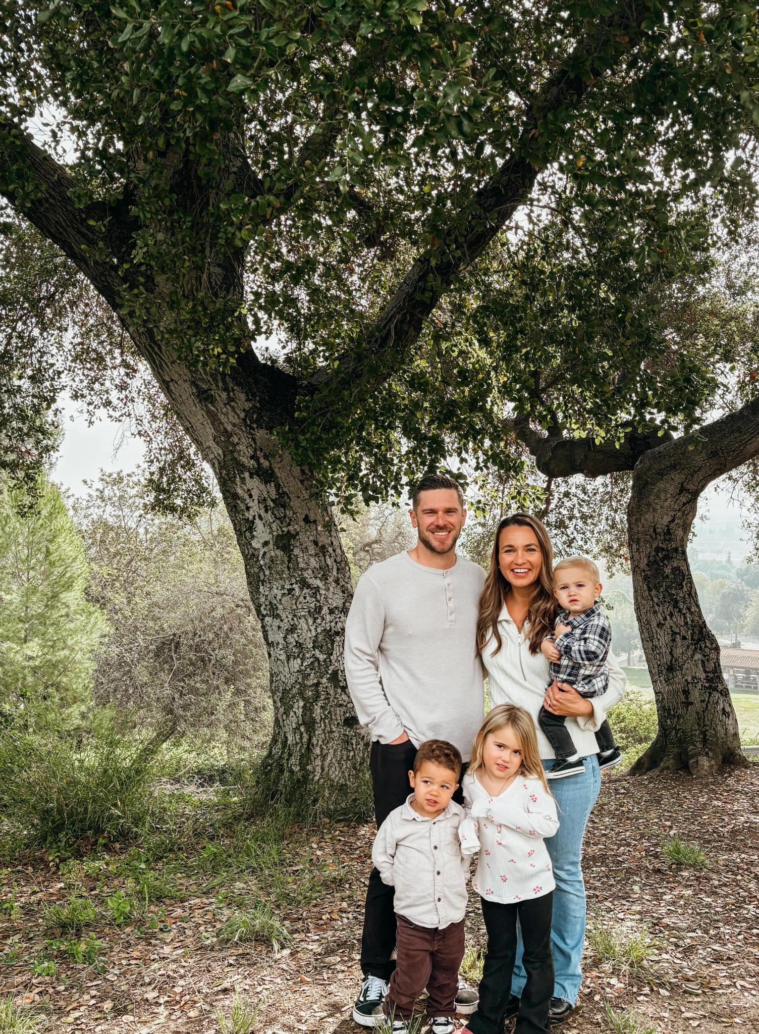 Kevin with his wife and children standing beneath a tree